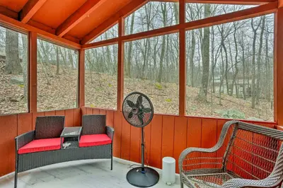 a screened in porch with two chairs and a fan at 4 Mi to Tubing Cozy Bushkill Cabin with Deck! in Bushkill