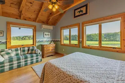 a bedroom with a bed and a couch and windows at Tenwood Lodge in Ithaca