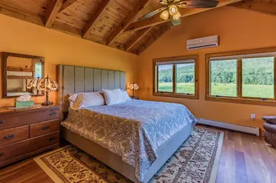 a bedroom with a bed and a dresser and windows at Tenwood Lodge in Ithaca