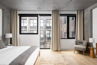 a bedroom with a bed and a chair and windows at Stunning Penthouse in Chelsea in New York