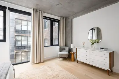 a bedroom with a bed and a dresser and windows at Stunning Penthouse in Chelsea in New York