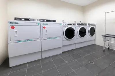 three washing machines in a room with a tile floor at Synergy Chelsea in New York