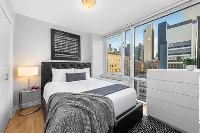 a bedroom with a bed and a large window at Synergy Chelsea in New York