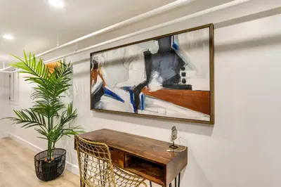 a painting hanging on a wall with a wooden table at Jersey City Vacation Rental Near Light Rail! in Jersey City