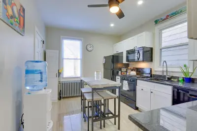 a kitchen with white cabinets and a table with chairs at Jersey City Apartment Near Liberty State Park in Jersey City