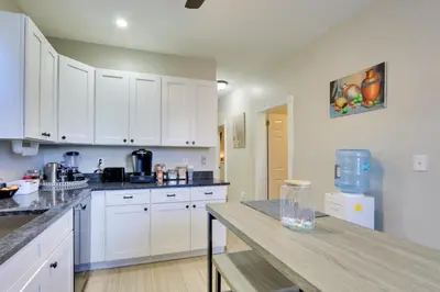 a kitchen with white cabinets and a wooden table at Jersey City Apartment Near Liberty State Park in Jersey City