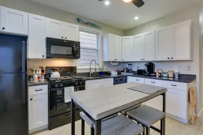 a kitchen with white cabinets and a table in it at Jersey City Apartment Near Liberty State Park in Jersey City