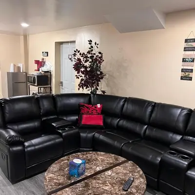 a black leather couch in a living room with a table at The McNeil Mansions in Harrisburg