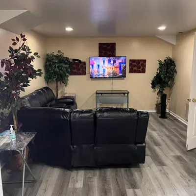 a living room with a black leather couch and a flat screen tv at The McNeil Mansions in Harrisburg
