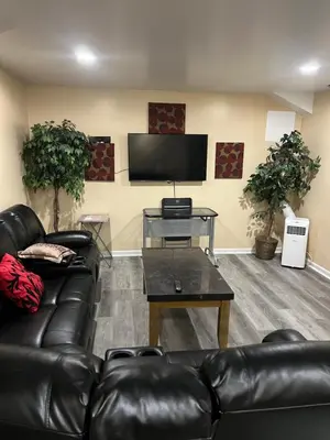 a living room with a leather couch and a flat screen tv at The McNeil Mansions in Harrisburg