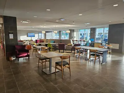 a restaurant with tables and chairs in a cafeteria at Home2 Suites By Hilton Allentown Bethlehem Airport in Bethlehem