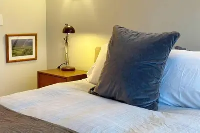 a bed with a blue pillow on top of it at Hÿgge House in Margaretville