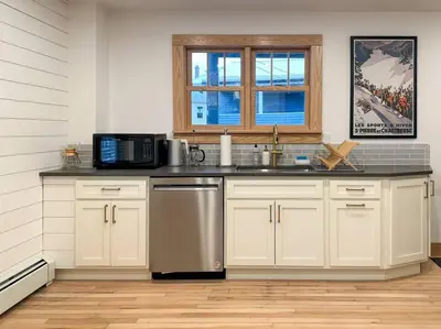 a kitchen with white cabinets and a sink and a microwave at Hÿgge House in Margaretville