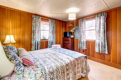 a bedroom with a bed and two windows at Pet-Friendly Home with Deck at Big Bass Lake! in Gouldsboro
