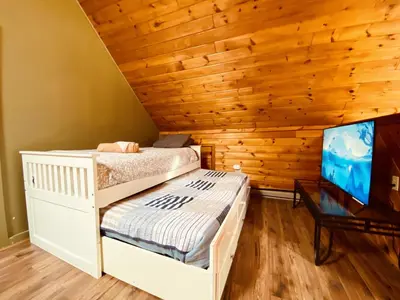 a bedroom with two bunk beds and a flat screen tv at Knoll by the Lake-7 minutes to skiing in Lake Harmony
