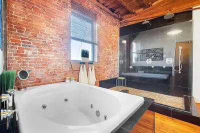 a large white tub in a bathroom with a brick wall at World Cup 2026 Luxury Industrial Loft in Philadelphia