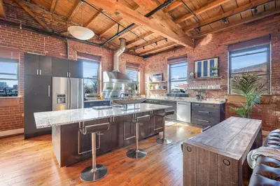 a large kitchen with a brick wall and wooden ceilings at World Cup 2026 Luxury Industrial Loft in Philadelphia