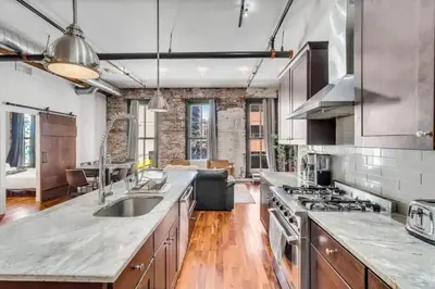 a kitchen with wooden floors and a brick wall at The Independence Suite Residence in Philadelphia