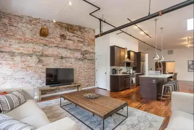 a living room with a brick wall and a table at The Liberty Suite Residence in Philadelphia