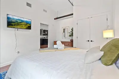 a white bedroom with a large bed and a tv on the wall at The Heritage Suite Central Old City Near the Liberty Bell in Philadelphia