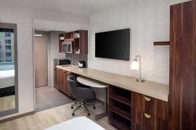 a hotel room with a desk with a tv on the wall at Home2 Suites By Hilton New York Times Square in New York