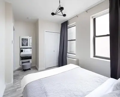 a white bedroom with a bed and two windows at Modern Spacious Apartment in Chelsea in New York