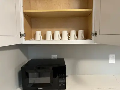 a black microwave in a kitchen with white cabinets at J2 Pleasant Queens Size room near St. Peter's hospital & New Brunswick Downtown in New Brunswick