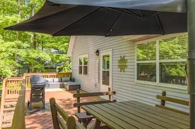 a porch with a picnic table and an umbrella at Cozy Pocono Getaway In Arrowhead Lake in Thornhurst