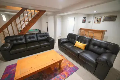 a living room with a black leather couch and a table at Cozy Pocono Getaway In Arrowhead Lake in Thornhurst