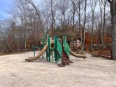 a playground with a slide in a park at Stylish and Cozy Cabin, Walking Distance to Big Bass Lake in Gouldsboro