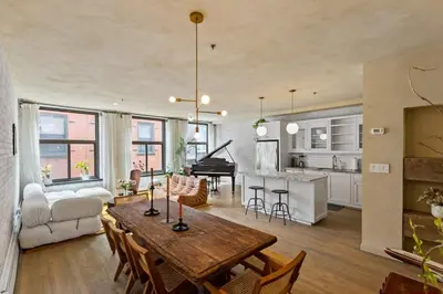 a living room and kitchen with a table and a piano at Tribeca Loft Vanderbilt by RoveTravel in New York