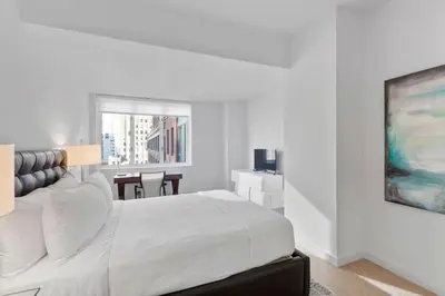 a white bedroom with a large bed and a table at Rector Place in New York
