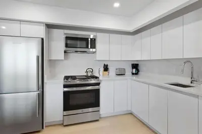 a white kitchen with a stove and a refrigerator at Rector Place in New York