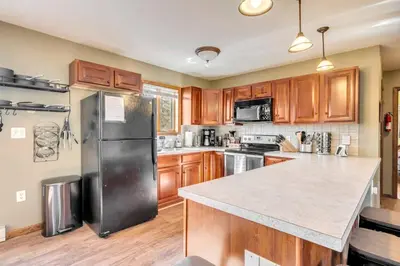 a kitchen with wooden cabinets and a black refrigerator at Steps To The Lake House, Hot tub, Game room, Deck in Albrightsville