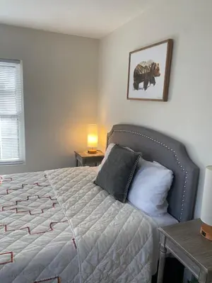a bedroom with a bed and a table with a lamp at Peaceful Seasonal Wooded Cottage close to everything in Tafton
