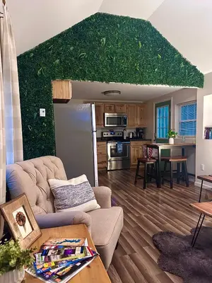 a living room with a couch and a kitchen at Peaceful Seasonal Wooded Cottage close to everything in Tafton