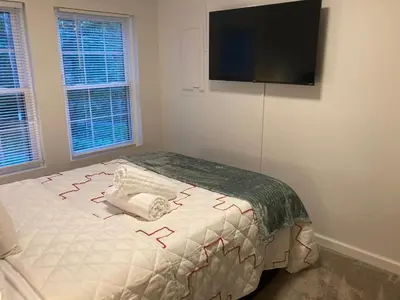 a bedroom with a bed with a flat screen tv on the wall at Peaceful Seasonal Wooded Cottage close to everything in Tafton