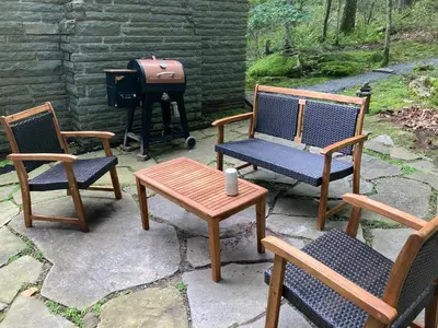 a group of chairs and a grill with a table and a stool at Peaceful Seasonal Wooded Cottage close to everything in Tafton
