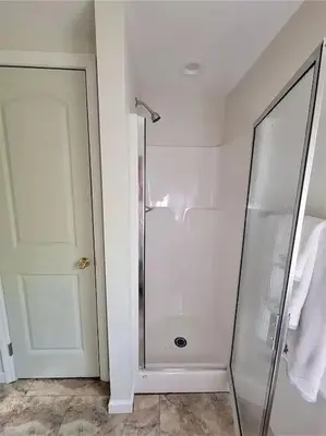 a bathroom with a shower and a glass door at Peaceful Seasonal Wooded Cottage close to everything in Tafton