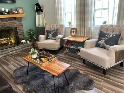 a living room with two chairs and a fireplace at Peaceful Seasonal Wooded Cottage close to everything in Tafton