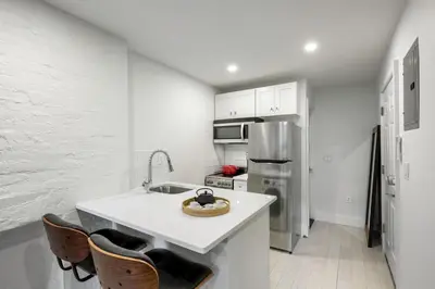a white kitchen with a sink and a refrigerator at E Village Studio w renovated virtual doorman NYC-316 in New York