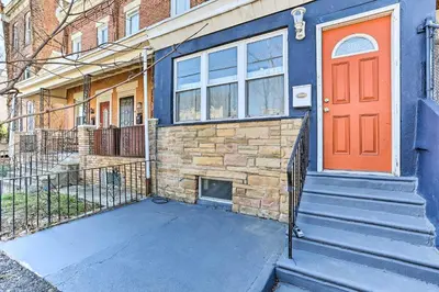 a blue house with an orange door and stairs at Philadelphia Home Rental Near Center City! in Philadelphia