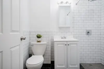 a white bathroom with a toilet and a sink at 74-4A 2BR 2baths in Prime Upper West Side w d GYM in New York