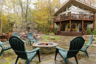 a patio with chairs and a fire pit in front of a house at Lake Naomi Chalet - 2hrs from NYC in Pocono Pines