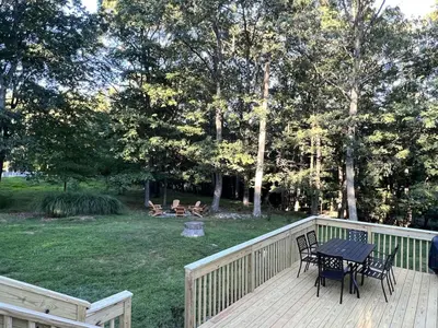 a wooden deck with a table and chairs on a yard at AMAZING Home with PRIVATE POOL, GAME ROOM & FIRE PIT! in East Stroudsburg