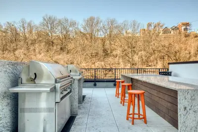 a patio with a grill and orange bar stools at Hoboken 2BR w PATH Shuttle Gym WD NYC-813 in Hoboken