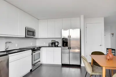 a white kitchen with a stainless steel refrigerator at Hoboken 2BR w PATH Shuttle Gym WD NYC-813 in Hoboken