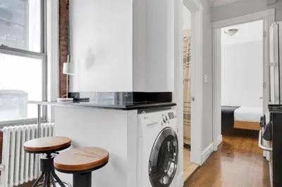 a kitchen with a washing machine and two stools at E Village 1BR w in-unit WD nr Park NYC-722 in New York