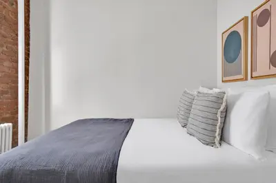 a bedroom with a bed with white sheets and pillows at E Village 1BR w in-unit WD nr Park NYC-722 in New York