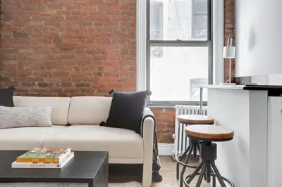 a living room with a couch and a brick wall at E Village 1BR w in-unit WD nr Park NYC-722 in New York